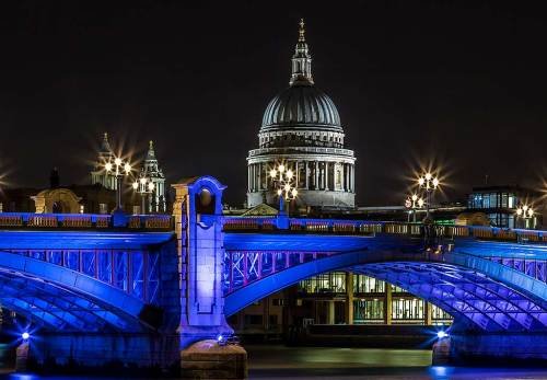London Bridge and St Pauls Cathedral Building Reflected in River Thames at night in Blue Lights