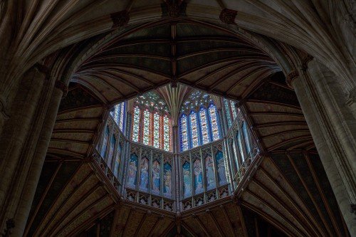 Ornate carved ceiling and stained glass windows in Ely Cathedral in England
